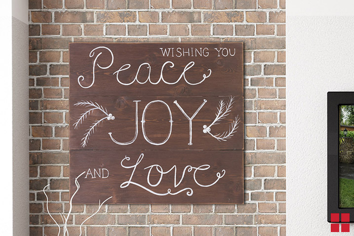 Wood sign stained brown and painted with the words, “Wishing you peace, joy and love.