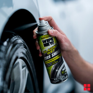 Person spraying Wipe New Blazing Wet Tire Shine on a tire.