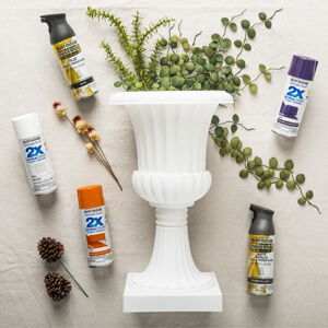 White urn surrounded by greenery and cans of Rust-Oleum spray paint.