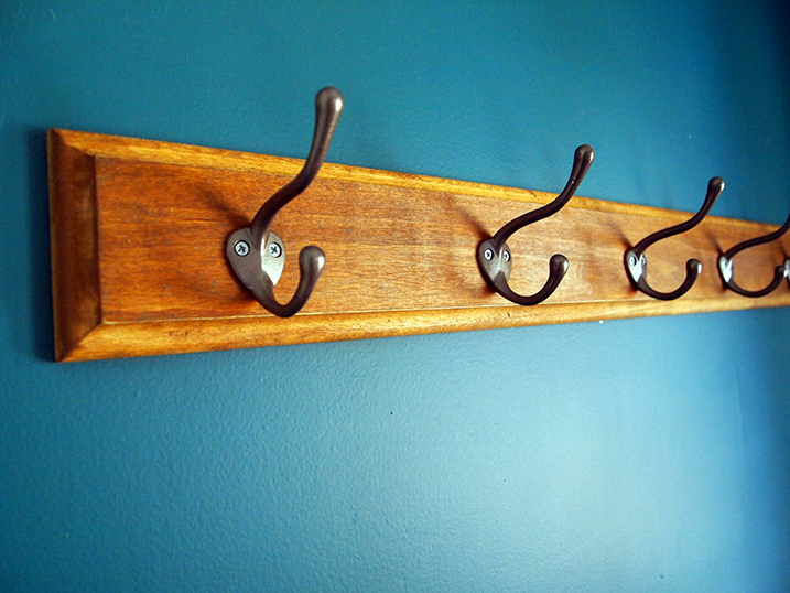 Wall-mounted wood coat rack with metal hooks. 