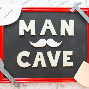 Man cave sign decorated with a mustache, tools, football and coffee cup.