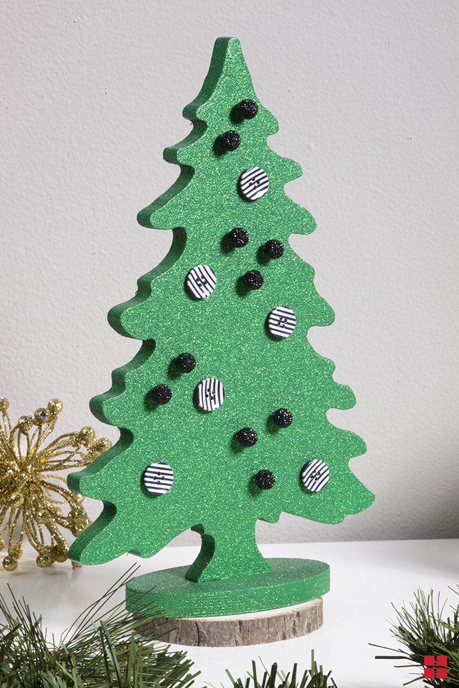 Glittery green wooden tree with buttons as ornaments.
