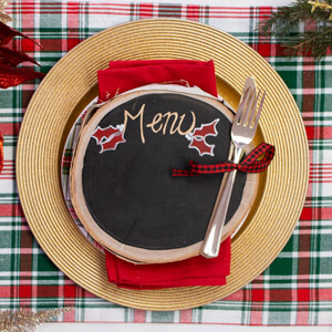 A round chalkboard with “menu” written on top and placed over a place setting.