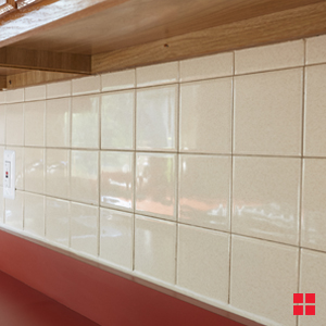 An off-white tile backsplash above a dark red countertop.