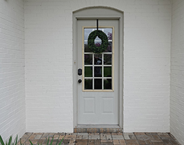 Beige front door with white brick walls on either side.