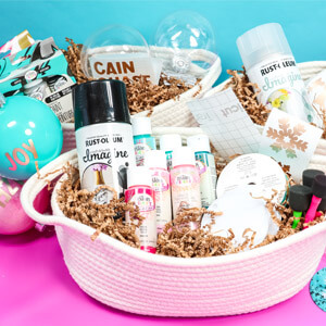 Painted ornaments on a table next to three white baskets containing Rust-Oleum and Testors paint products. 