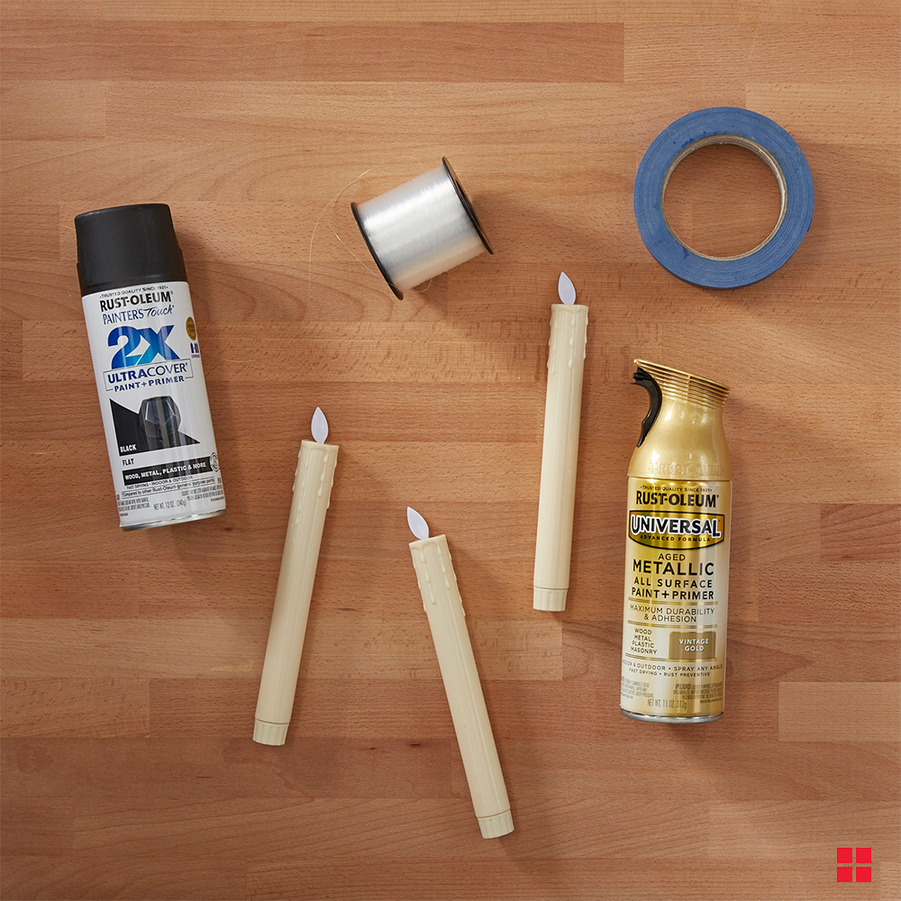 Two cans of Rust-Oleum spray paint, plastic candlesticks, painter’s tape and a roll of fishing wire.