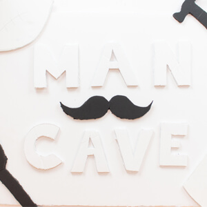 Unpainted letters and shapes on unfinished man cave sign.