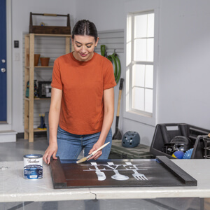 Woman applying Varathane Polyurethane over stained and painted noodle board.
