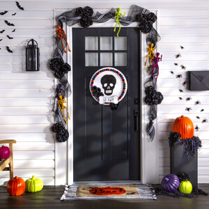 Halloween garland, painted pumpkins and fake bats and spiders around a black front door. 
