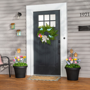 A front porch with urn planters on either side and a spring wreath on the front door. 