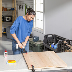 Woman screwing wood boards together.