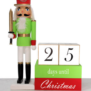 A red and green Nutcracker figurine next to wooden blocks that say 25 days until Christmas.
