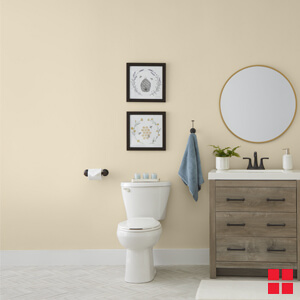 A toilet and sink in a bathroom with walls painted a creamy beige color. 