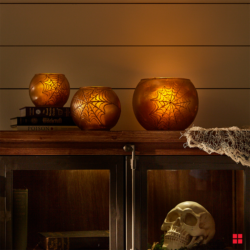 Three votive holders painted with a spider web design.
