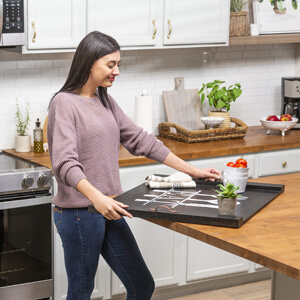 Woman placing completed noodle board on kitchen countertop.