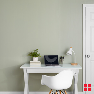 A white desk against a green wall.