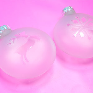 Two frosted glass ornaments, one with a deer and the other with a snowflake on it. 