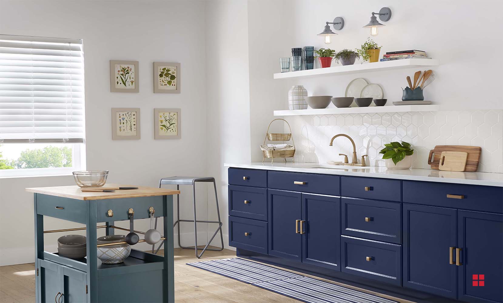 A green kitchen island cart in the middle of a kitchen with white walls and navy blue cabinets.