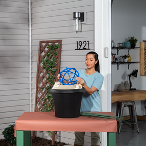 A woman placing a blue orb in an urn planter. 