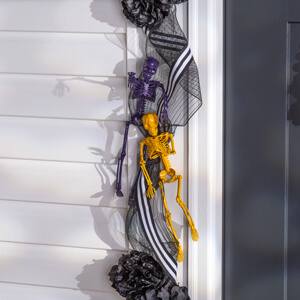 Purple and yellow skeletons attached to Halloween garland. 