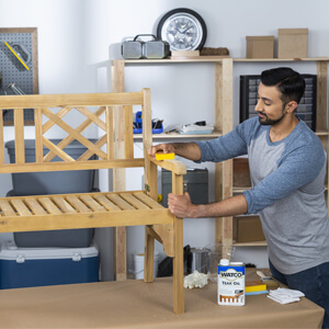 Man sanding a wood bench.