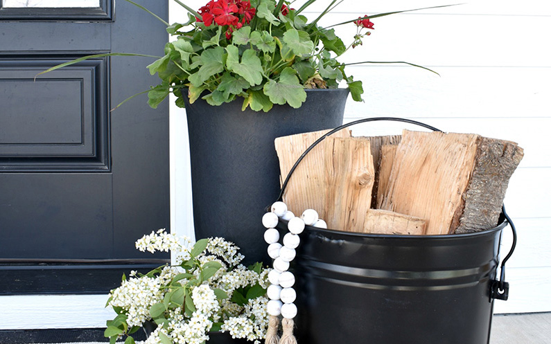 Black metal bucket and planter on a front porch.