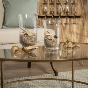 Gold painted seashells on a table next to vases filled with sand and shells.