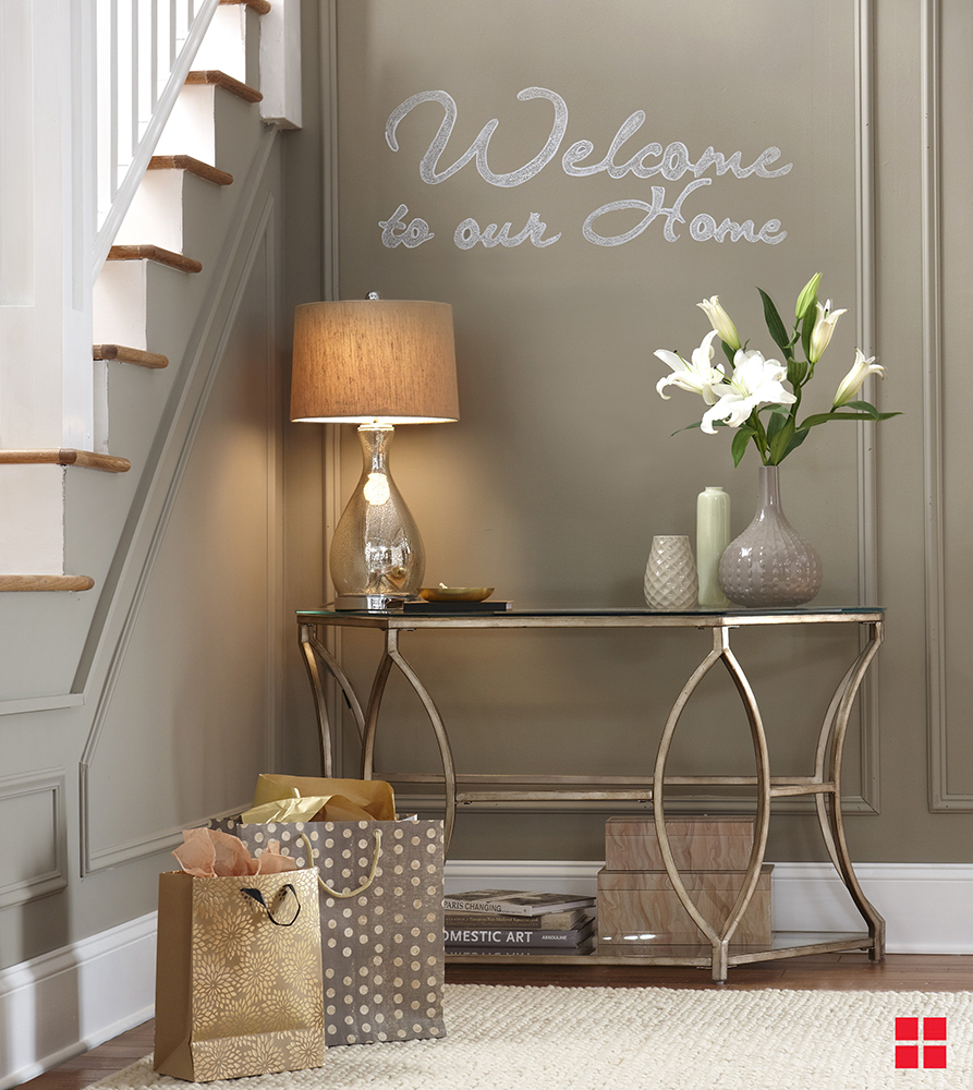 “Welcome to our home” written in chalk on a brown entryway wall.