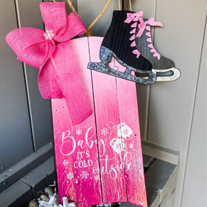 A vintage wooden sled painted with a pink ombre effect. 