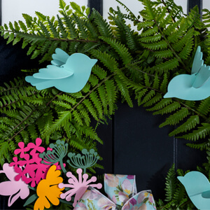 Decorative blue birds and pink and yellow flowers on a green wreath.