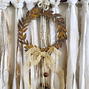 A rusty looking brown wreath with an off-white bow.