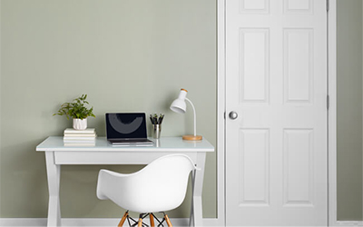 A white desk against a green wall.
