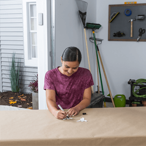 Woman decorating wooden ghost with paint pen.