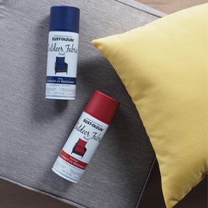Cans of red and blue Rust-Oleum Outdoor Fabric Paint next to a yellow pillow and gray patio cushion.