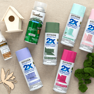 Unpainted wooden birdhouse, decorative wooden flowers, green moss, a bottle of Varathane Less Mess Wood Stain, 6 cans of Rust-Oleum 2X Ultra Cover Spray Paint and a spray can of Varathane Spar Urethane. 