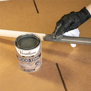 Applying Varathane wood stain to dowel rod with a rag.