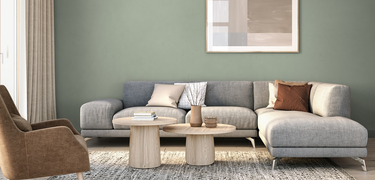 A couch and chair in front of a sage green wall.