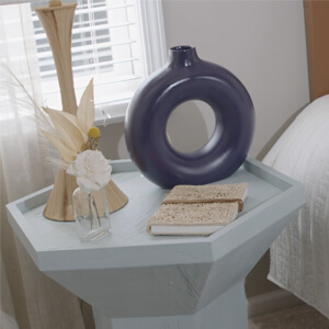 Light blue wood night stand next to a bed. 