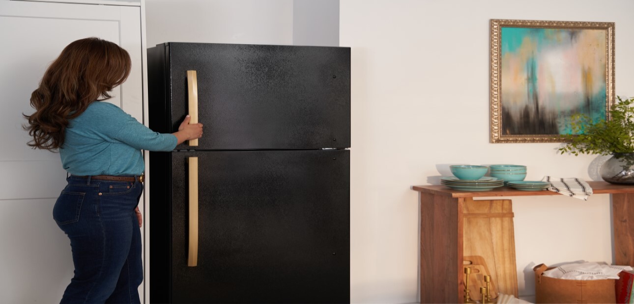 A woman opening a black freezer with a gold handle