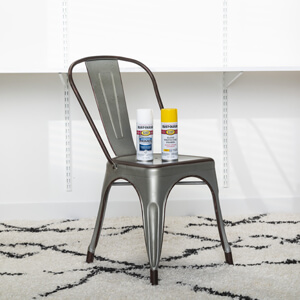 Gray metal chair with two cans of spray paint on the seat.