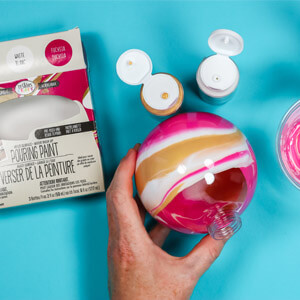Swirling pink, white and gold Testors Pouring Paint inside a round, glass ornament.