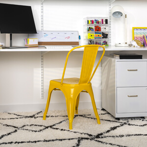 A home office space with a bright yellow metal chair.