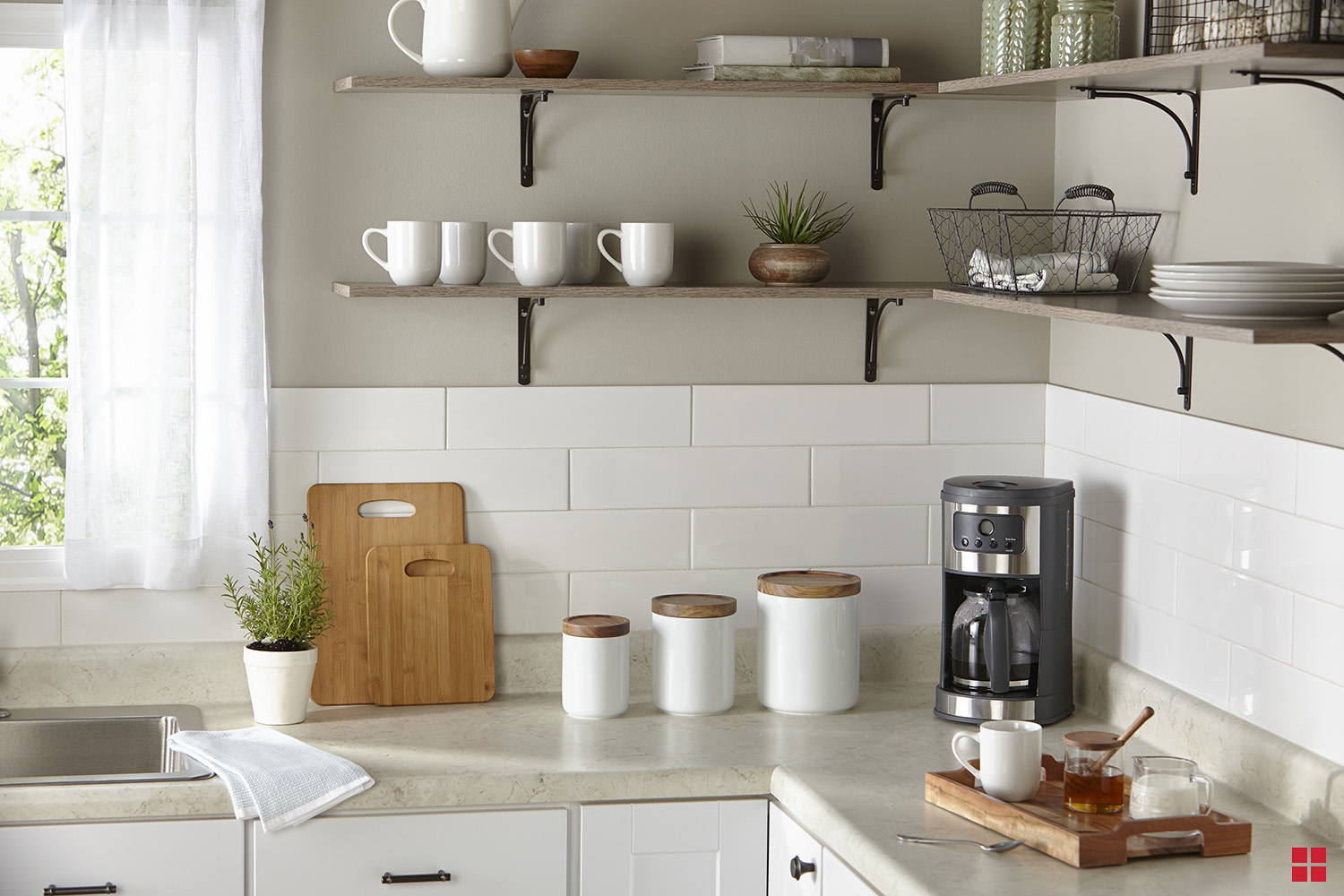 Three white canisters between cutting boards and a coffee maker on the kitchen counter.