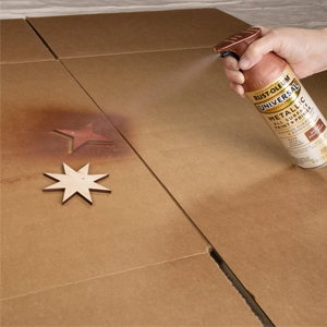 Applying Rust-Oleum Universal Metallic spray paint to small wood pieces.