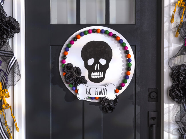 Black skull painted on a round white sign. 