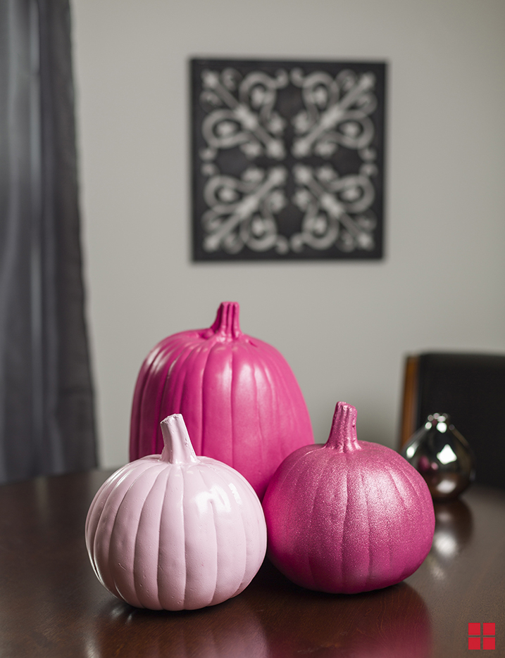Three pink pumpkins on a table.