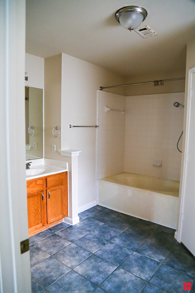 Bathroom with a wood vanity and a blue tile floor. 