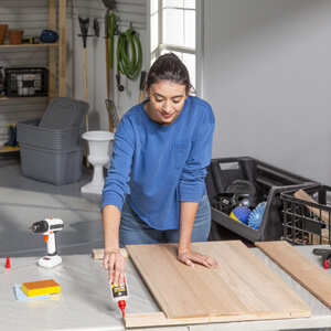 Woman applying glue to wood board.