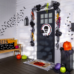 Front porch decorated for Halloween with garland and painted pumpkins.